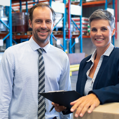 Ein Unternehmer und eine Unternehmerin in der Lagerhalle ihres Betriebes
