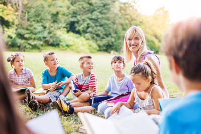 Eine Lehrerin unterrichtet eine Gruppe Kinder im Freien