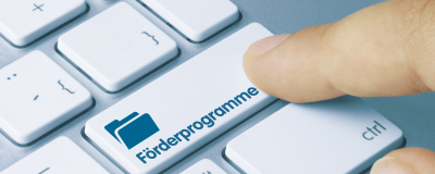 Ein Finger drückt auf einer Tastatur die Taste Förderprogramme