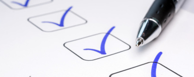 Nahaufnahme eines Stiftes und Papieres auf dem Punkte abgehakt wurden